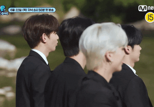 a group of young men in suits are standing in a line with a mnet logo in the corner