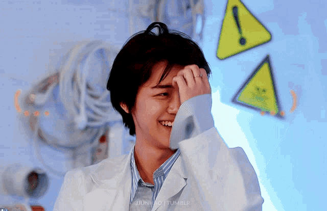 a man in a lab coat is smiling in front of a sign that says danger