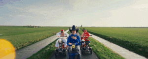 a man in a cowboy hat is riding a scooter down a road