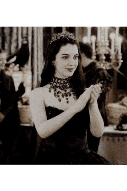 a black and white photo of a woman in a black dress with a tiara on her head