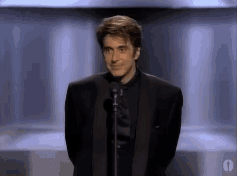 a man in a suit is standing in front of a microphone .