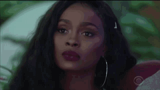 a close up of a woman 's face wearing hoop earrings and purple lipstick .