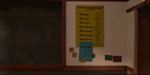 a green cartoon character is standing in front of a blackboard with a ruler .