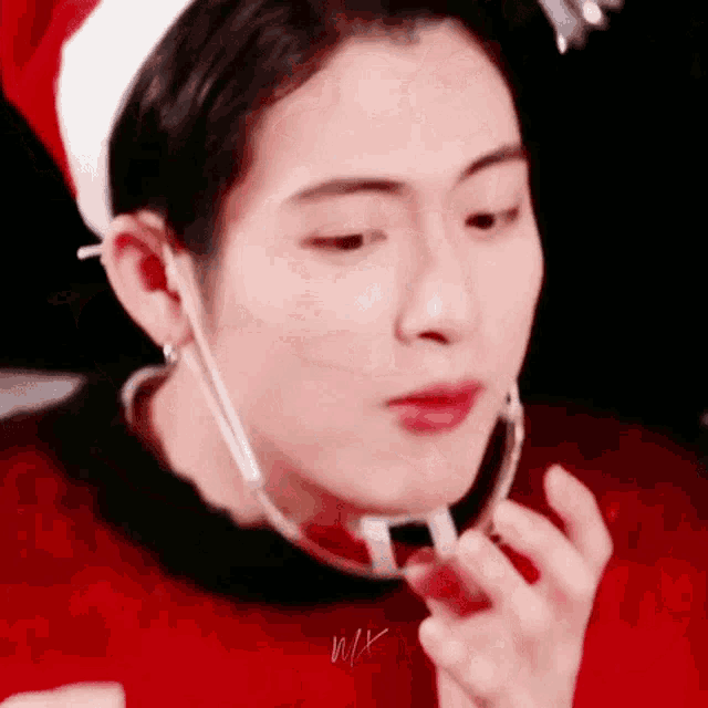 a young man wearing a santa hat and a red sweater is eating a piece of chocolate .