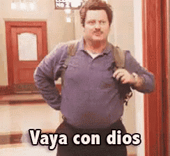 a man in a blue shirt is standing in a hallway and says vaya con dios