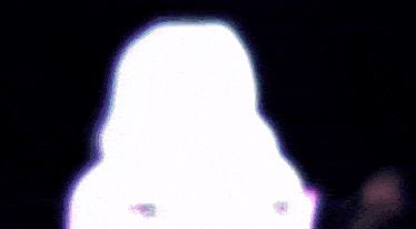 a woman is dancing in a dark room with a purple light coming out of her hair .