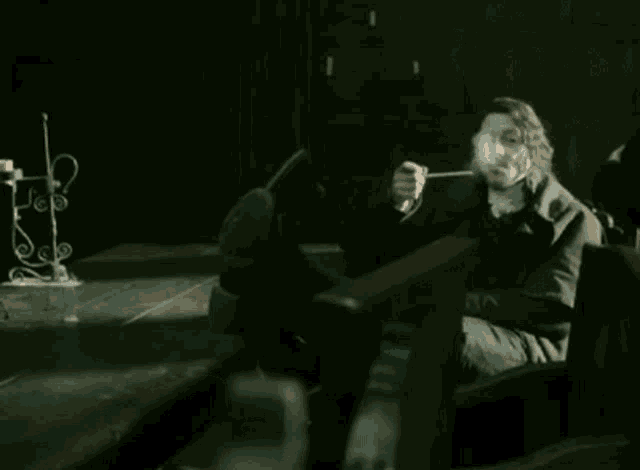 a man is smoking a pipe in a dark room .