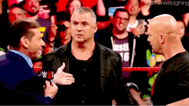 a man in a black shirt with the number 16 on it is talking to another man