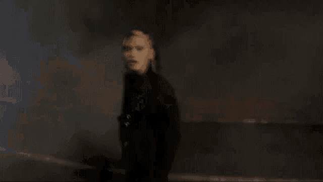 a woman is singing into a microphone in a dark room with smoke coming out of her mouth .