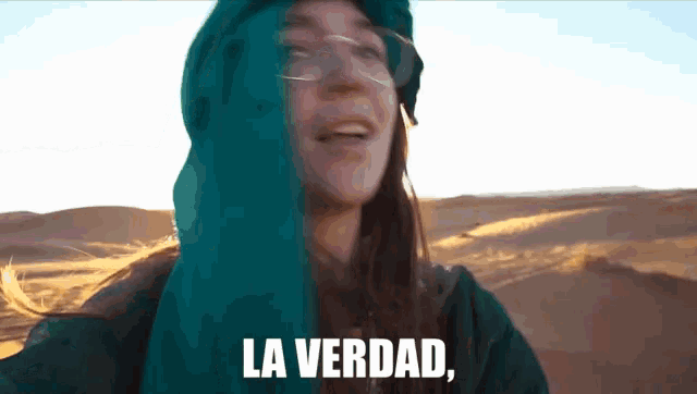 a woman wearing glasses and a blue hood says la verdad in front of a desert