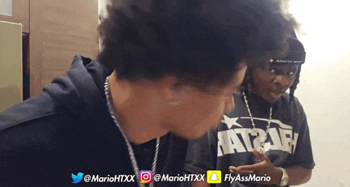 a man wearing a mario htxx shirt stands next to another man wearing a fly ass mario shirt