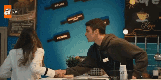 a man and a woman are shaking hands in front of a tv sign