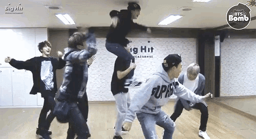 a group of young men are dancing in a room with the word big hit on the wall