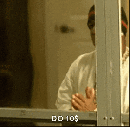 a man in a white shirt is standing in front of a window with the words do 10 $ written on it .
