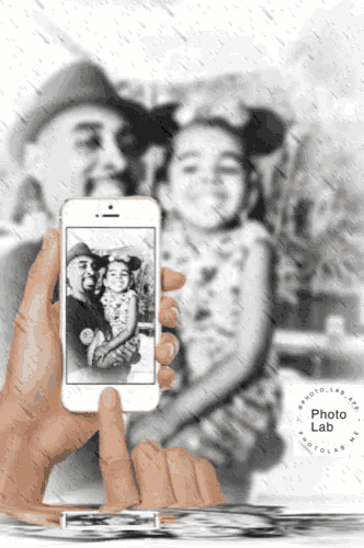 a hand is holding a cell phone with a picture of a man and a little girl on the screen