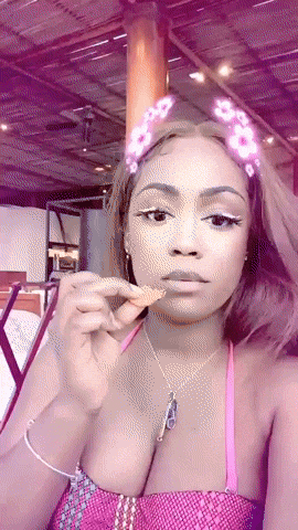 a woman wearing a headband with flowers on it is eating a chip