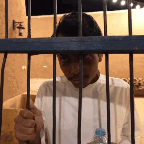 a man behind bars with a bottle of water in his hand