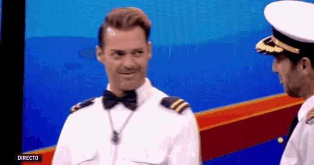 a man in a bow tie is standing next to another man in a uniform with the word directo on the bottom right