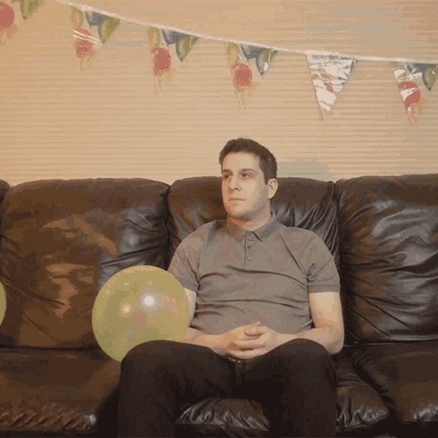 a man is sitting on a couch with balloons on it