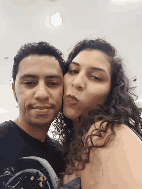 a man and a woman are posing for a picture and the woman is kissing the man