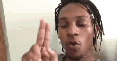 a man with dreadlocks is making a funny face with his fingers .