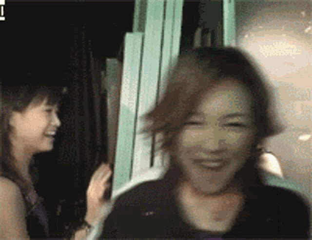 two women are standing next to each other and one is smiling .