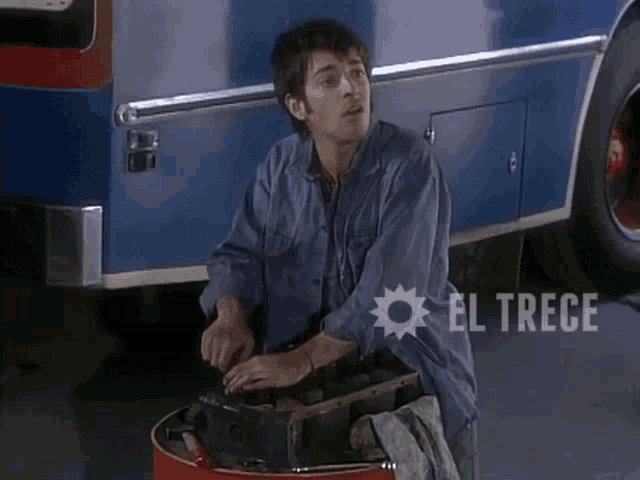 a man is working on a vehicle with el trece written on the bottom of the image