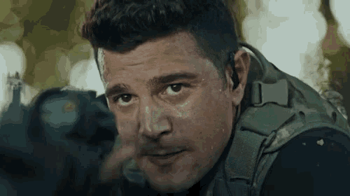 a close up of a man 's face with a sniper rifle in the background