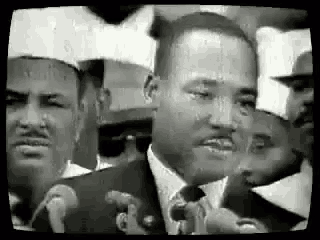 martin luther king jr. is giving a speech in front of a crowd of people .