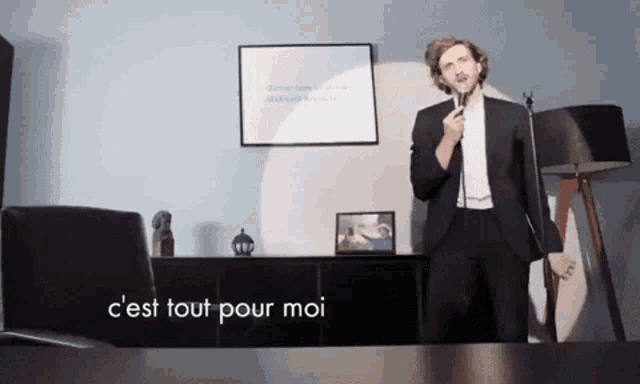 a man in a suit singing into a microphone with the words c'est tout pour moi above him