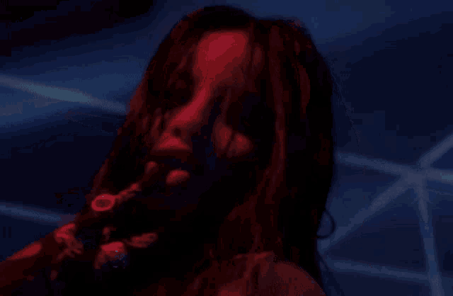 a close up of a woman 's face in a dark room with red lights .