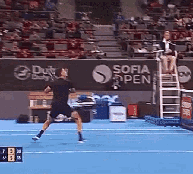 a man is running on a tennis court in front of a sofia open sign .