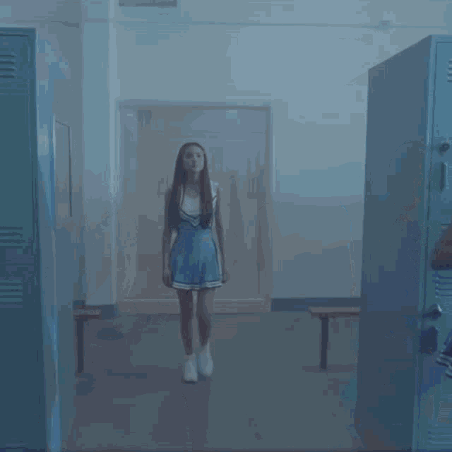 a cheerleader is standing in a locker room with other cheerleaders .