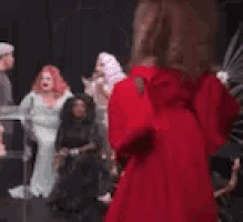 a drag queen is standing on a stage holding a microphone and saying `` rigged america '' .