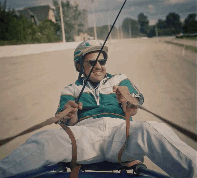 a man wearing a helmet and sunglasses is riding a blue cart