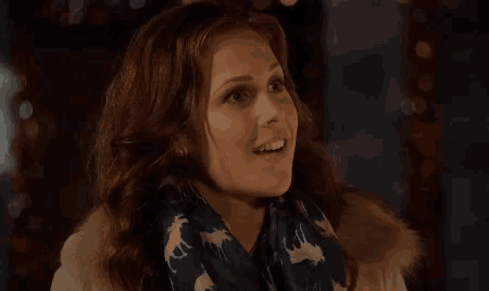 a woman wearing a scarf with deer on it and a fur coat is smiling .