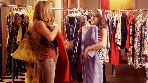 two women are shopping in a clothing store .