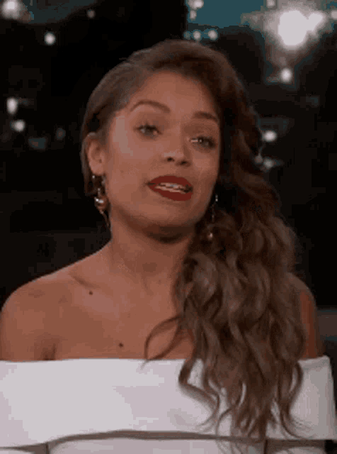 the woman is wearing a white off the shoulder top and red lipstick