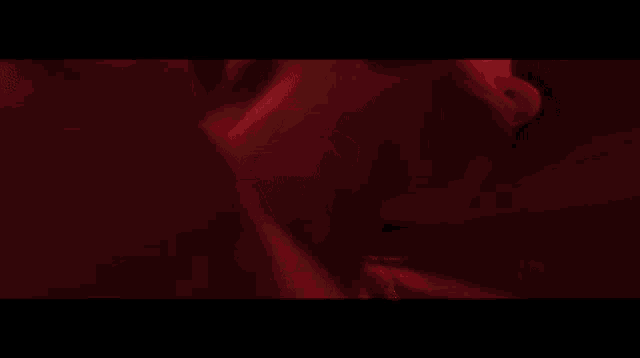 a man is playing a guitar in front of a red wall
