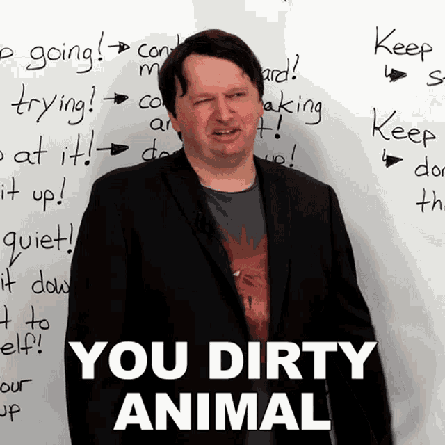 a man stands in front of a white board that says " you dirty animal " on it