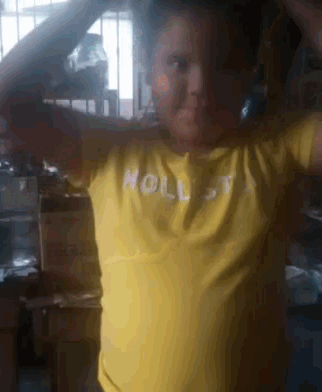 a boy wearing a yellow hollister shirt is standing in front of a window