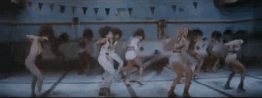 a group of women are dancing in a pool in a dark room .