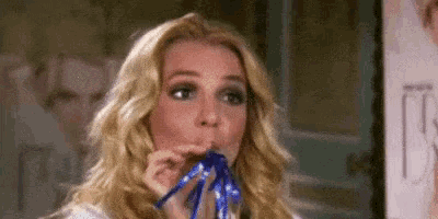 a woman is blowing a party horn with a blue ribbon .