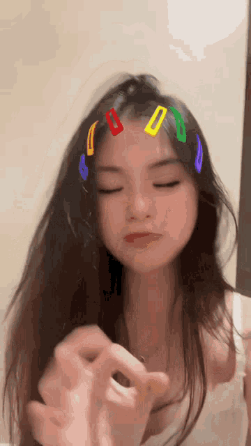 a girl with colorful hair clips on her head is making a funny face .