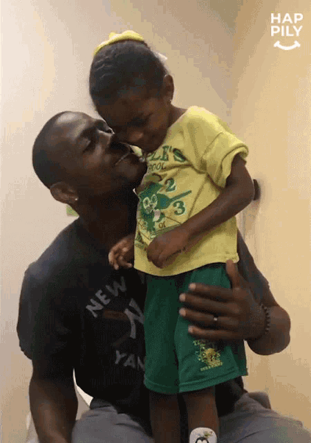 a man in a new york yankees shirt is kissing a little girl