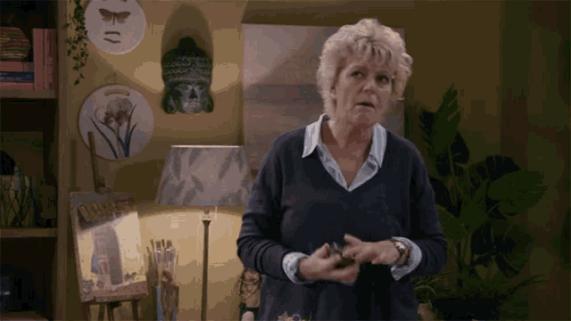 a woman in a living room with a lamp and a painting on an easel that says ' flowers '