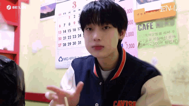 a boy is sitting in front of a calendar that says cafe