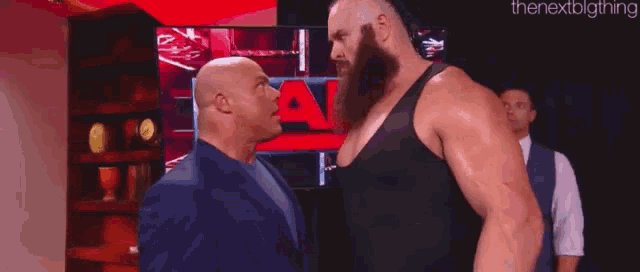a bald man and a bearded man are standing next to each other .
