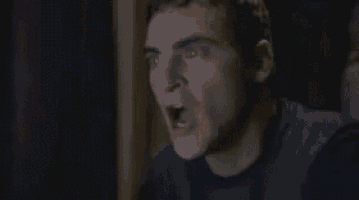 a close up of a man 's face with his mouth open in a dark room .