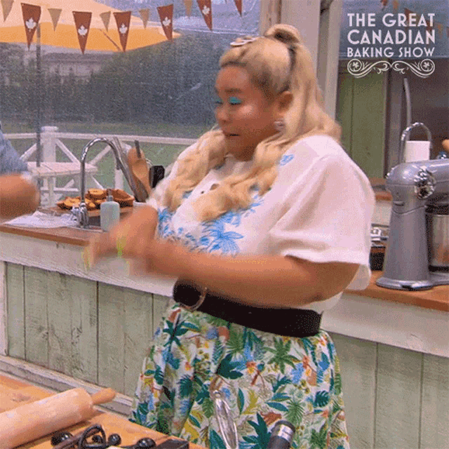 a woman is standing in a kitchen in front of a sign that says the great canadian baking show .